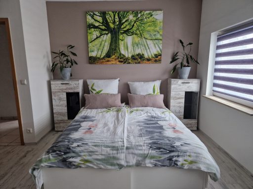 Doppelbett mit Orchideenbettwäsche , Bild mit großen grünen Baum 